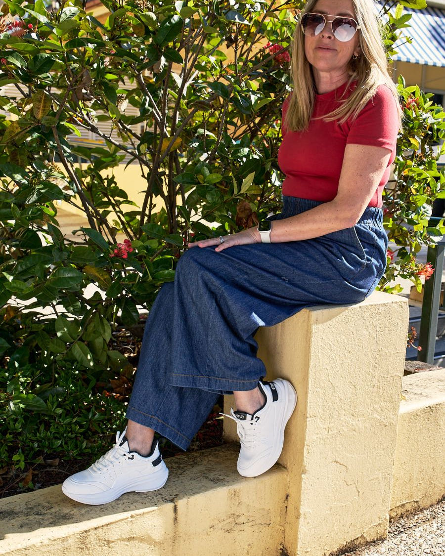 A woman sat down wearing white walking shoes