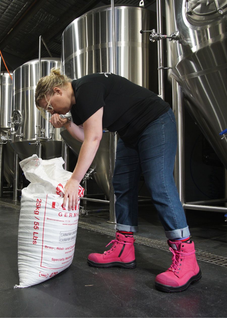 Woman working in brewery wearing pink lace-up composite boots. 