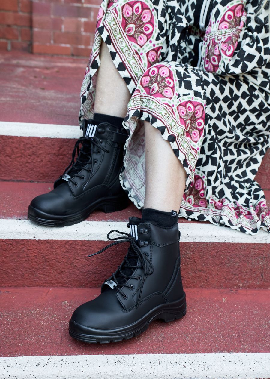 Up close photo of black work boots on concrete steps