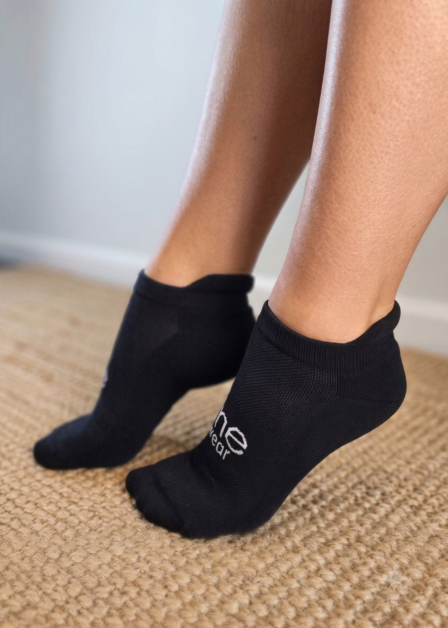 a pair of feet wearing black ankle socks with extra heel padding