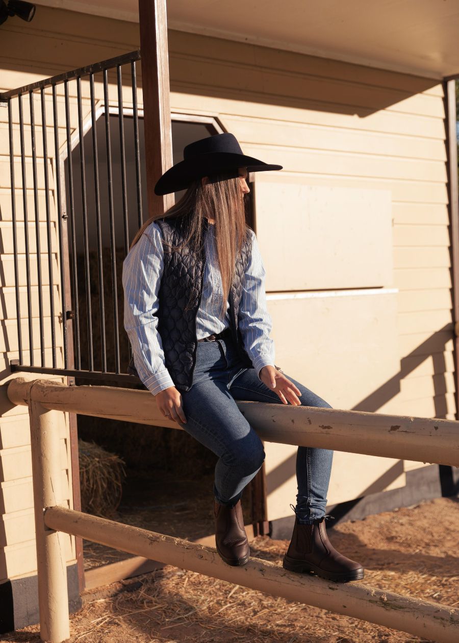 Woman in barn sat down wearing brown boots