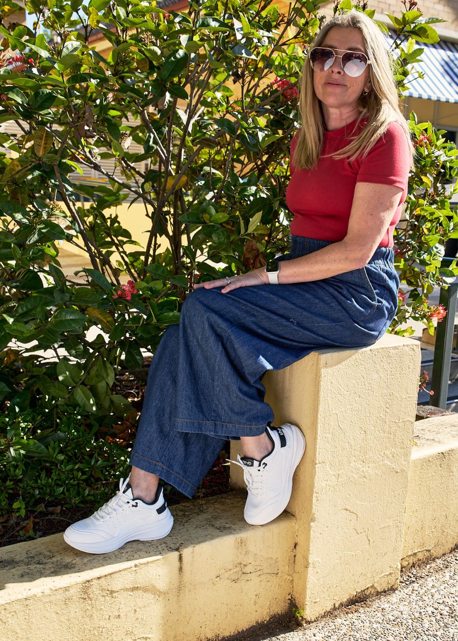 A woman sat down wearing white walking shoes 